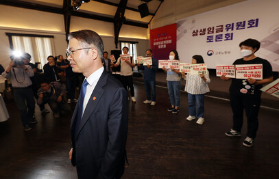 이정식 고용노동부 장관이 5월23일 오후 서울 중구 정동 1928아트센터에서 열린 상생임금위원회 토론회에 참석한 가운데 비정규직 임금 대폭 인상, 노동시장 이중구조 해결 등을 촉구하는 노동계 기습시위가 진행되고 있다. 연합뉴스