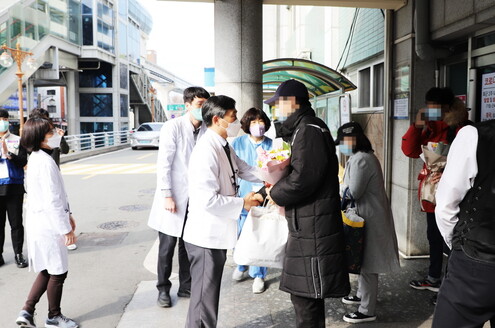 지난 29일 오후 대구 중구 계명대 대구동산병원 앞에서 병원 의료진과 직원들이 퇴원하는 코로나19 완치자 3명에게 꽃다발을 건네며 축하하고 있다. 계명대 동산의료원 제공