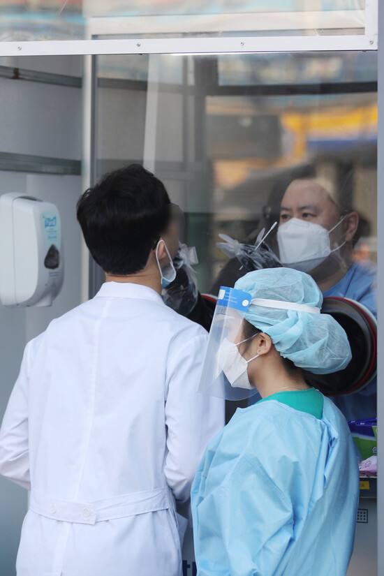 14일 오전 광주 동구 전남대병원 선별진료소에서 의료진이 신종 코로나바이러스 감염증(코로나19) 검사를 받기 위해 문진표를 작성하고 있다. 전남대병원 전공의가 전날 밤 코로나19 확진 판정을 받으면서 일부 시설 출입이 통제되고 동료 의료진과 환자 등이 진단 검사를 받고 있다.연합뉴스