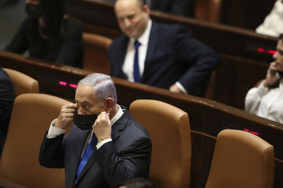 이임하는 베냐민 네타냐후 총리(앞쪽)가 13일 이스라엘 의회에서 개의를 기다리며, 후임 총리로 지명된 나프탈리 베네트(뒤쪽) 앞줄에 앉아 마스크를 고쳐 매고 있다. 예루살렘/AP 연합뉴스