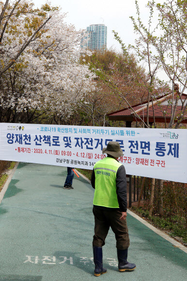 지난 12일 서울 양재천 산책로 들머리에 ‘코로나19' 확산 방지를 위한 진입 통제 안내 펼침막이 걸려 있다. 연합뉴스