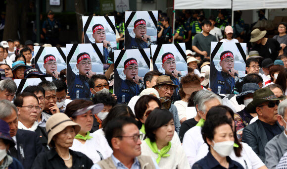 지난 10일 오후 서울시청 앞 도로에서 열린 제32회 민족민주열사·희생자 범국민 추모제에서 참가자들이 분신해 숨진 건설노조 강원지부 간부 양회동 씨의 사진을 들고 있다. 연합뉴스