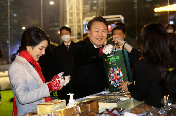 윤석열 대통령과 김건희 여사가 16일 오후 서울 종로구 열린송현광장에서 열린 윈·윈터 페스티벌 개막식에서 에어돔 부스를 방문, 물건을 구입하고 있다. 연합뉴스