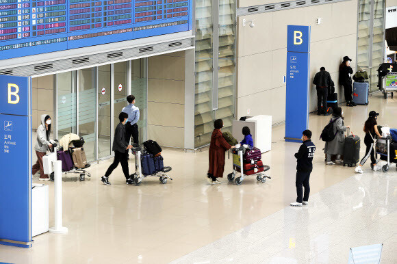 정부가 27일부터 미국발 입국자에 대한 검역을 강화하기로 했다. 25일 인천국제공항 제2터미널 입국장에서 방역당국 관계자가 유럽발 항공기 승객들을 살피고 있다. 연합뉴스