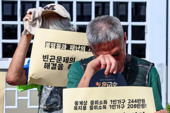 아침부터 일부 지역에 폭염경보가 발효된 28일 오전 서울 종로구 정부서울청사 앞에서 열린 기준중위소득 현실화 기자회견에서 참가자들이 더운 날씨에 모자를 벗거나 땀을 닦고 있다. 연합뉴스