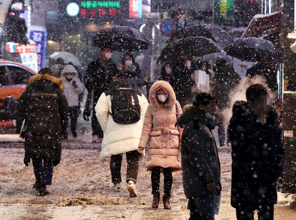 눈이 내린 12일 저녁 서울 강남역 인근에서 시민들이 퇴근길을 재촉하고 있다. 연합뉴스