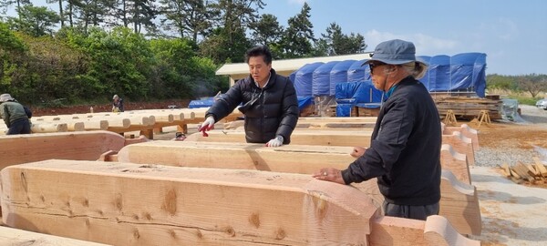 박병두 작가(왼쪽)가 지난해 해남군 송지면에 터를 잡은 뒤 목수들과 함께 한옥으로 인송문학촌을 짓는 작업을 하고 있다. 인송문학촌 제공