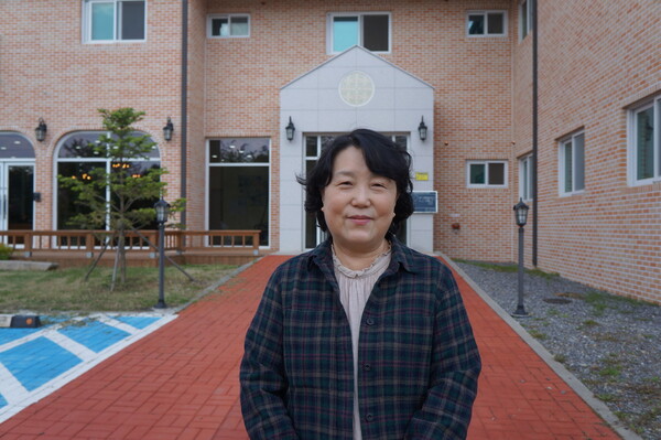 김미경 원장이 조이빌리지 신축 건물인 신관을 배경으로 사진을 찍고 있다. 영문학을 전공한 대학 시절부터 7년 동안 가톨릭학생회에서 야학을 했다는 김 원장에게 대학 시절 꿈이 뭐였냐고 묻자 ‘글 쓰는 사람’이었단다.   “전문 작가는 아니지만 기쁨터나 조이빌리지 활동을 하면서 제 생각을 다른 사람들에게 알리는 글을 많이 썼어요. 꿈을 이룬 거나 마찬가지죠. 대학 시절 야학할 때 섬에서 아이들을 가르치는 부부교사가 되고 싶다는 생각도 했는데, 기쁨터 자원봉사자들과 함께하는 캠프 때 ‘내가 바로 사람들 사이에서 섬처럼 살고 있다’는 생각이 들더군요.”                 강성만 선임기자