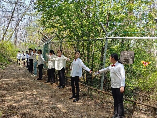 경기도 광명시 철산초등학교와 강원도 철원군 국경선평화학교, 숲나학교 학생 등 40여명이 철원 비무장지대(DMZ) 철망 앞에서 인간띠잇기를 하며 뮤직비디오 ‘디엠지 동산에서’를 촬영하고 있다. 국경선평화학교 제공