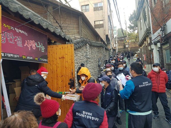 한국교회봉사단이 성탄절을 앞두고 지난 21일 서울 동자동 성민교회 앞에서 연 사랑나눔 행사에서 주민들에게 선물을 전달하고 있다. 한국교회봉사단 제공