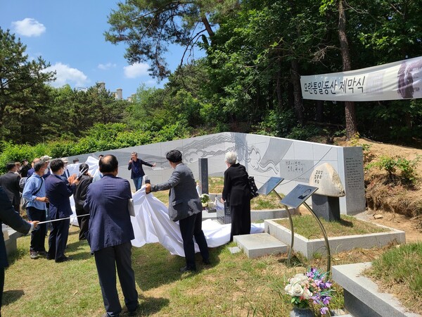 지난 6월11일 경기도 남양주시 마석 모란공원 문익환·정경모·유원호 선생 묘역에서 참가자들이 모란통일동산 추모벽을 제막하고 있다. 김경애 기자