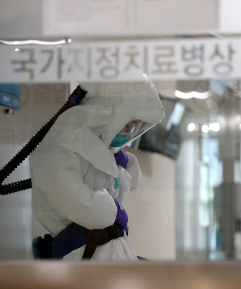 26일 오전 한 선별진료소에서 보건소 관계자가 코로나19 의심환자가 잠시 없는 사이 창밖을 바라보며 두 손을 모으고 있다. 연합뉴스