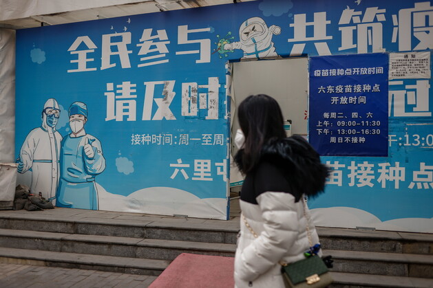 지난 2월11일 중국 베이징의 코로나19 예방 주사 접종처 앞을 한 여성이 지나가고 있다. 베이징/EPA 연합뉴스