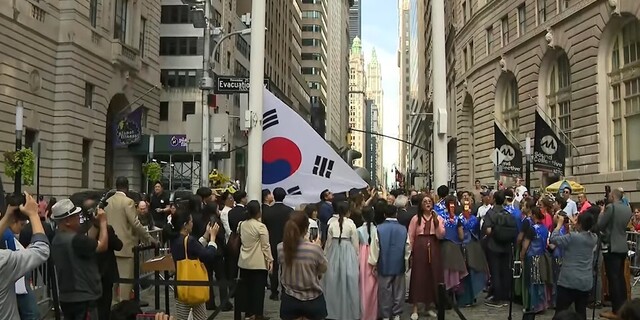 14일(현지시각) 미국 뉴욕 월스트리트의 ‘돌진하는 황소상’ 앞에서 에릭 애덤스 뉴욕시장(오른쪽)과 브라이언 전 재미차세대협의회(AAYC) 회장이 태극기를 게양하고 있다. 뉴욕시 유튜브 갈무리