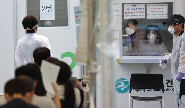 26일 서울 은평구 보건소 앞에 마련된 코로나19 선별진료소에서 보건소 관계자들이 부스 안에서 검사 대기자들을 살피고 있다. 연합뉴스