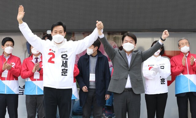 오세훈 국민의힘 서울시장 후보(앞줄 왼쪽)가 25일 서울 중구 덕수궁 대한문 앞에서 안철수 국민의당 대표와 손을 잡고 시민들에게 인사하고 있다. 김종인(뒷쪽 맨 오른쪽) 국민의힘 비상대책위원장은 박수를 치고 있다. 공동취재사진