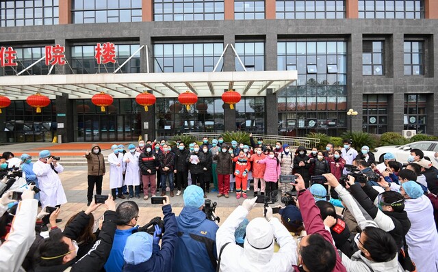 중국 후베이성 우한의 한 병원 앞에서 20일 코로나19 치료를 받고 완치돼 퇴원하는 환자들이 의료진과 기념사진을 찍고 있다. 신화 연합뉴스
