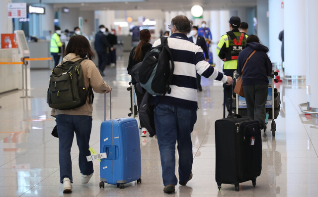 영국 런던발 항공편으로 입국한 외국인들이 24일 오후 인천국제공항 2터미널에 도착해 경찰의 인솔을 받아 임시생활시설로 가는 버스를 타려고 이동하고 있다. 연합뉴스