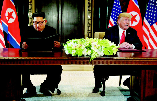 김정은 북한 국무위원장과 도널드 트럼프 미국 대통령이 2018년 6월12일 싱가포르에서 정상회담을 마무리한 뒤 공동성명 서명식을 하고 있다. 싱가포르/연합뉴스