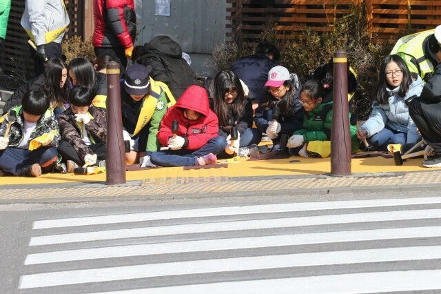 서울의 한 초등학교 어린이와 학부모들이 안전한 통학로 만들기 사업의 하나로 학교 앞에 ‘옐로카펫’을 설치하고 있다. 김정효 기자 hyopd@hani.co.kr