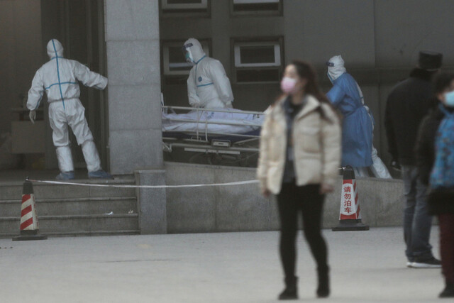 지난 20일 중국 후베이성 우한의 한 병원에서 방역복을 갖춰 입은 의료진이 신종 코로나 바이러스 감염에 따른 폐렴 의심 환자를 병실로 옮기고 있다. 로이터 연합뉴스