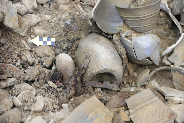 44호 무덤 부장궤에서 돌절구와 공이가 출토되는 모습.
