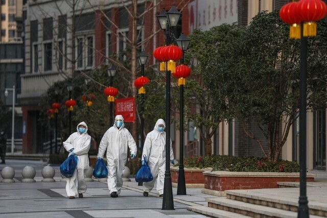 중국 후베이성 성도 우한에서 지난해 5월 방역요원들이 출입이 통제된 주민들에게 전달할 식재료를 들고 거리를 걷고 있다. 우한/AFP 연합뉴스