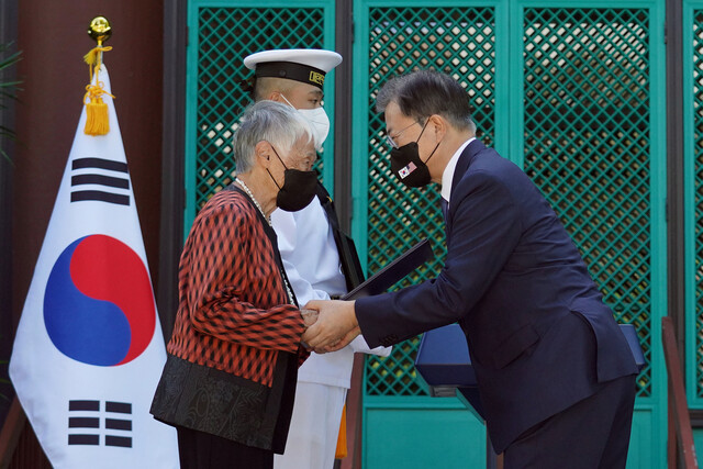 문재인 대통령이 22일(현지시각) 미국 하와이대 한국학 연구소에서 열린 독립유공자 훈장 추서식에서 독립유공자 김노디 지사 후손에게 애국장을 수여한 뒤 손을 잡고 있다. 연합뉴스