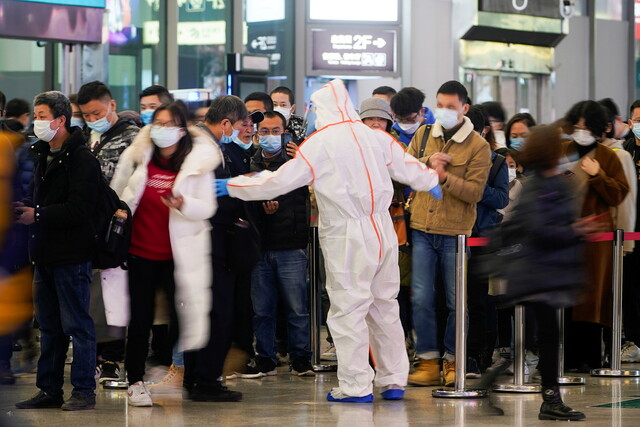 지난 25일 중국 상하이 훙차오역에서 방역요원이 건강상태 확인을 위해 승객들에게 휴대전화로 큐아르 코드를 스캔하라고 안내하고 있다. 상하이/로이터 연합뉴스