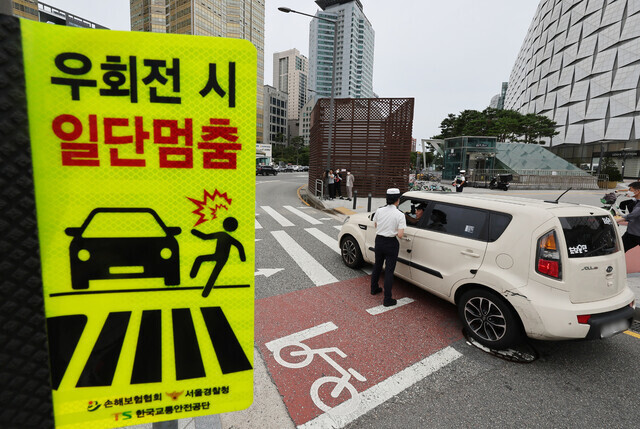 개정 도로교통법 시행 첫날인 지난 7월12일 서울 송파구 잠실역 교차로에서 송파경찰서 경찰관들이 계도 활동을 하고 있다. 연합뉴스