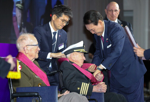 윤석열 대통령이 25일(현지시각) 워싱턴 한 호텔에서 열린 한-미 동맹 70주년 기념 오찬에서 앨머 로이스 윌리엄스 예비역 해군 대령에게 무공훈장을 친수하고 있다. 연합뉴스