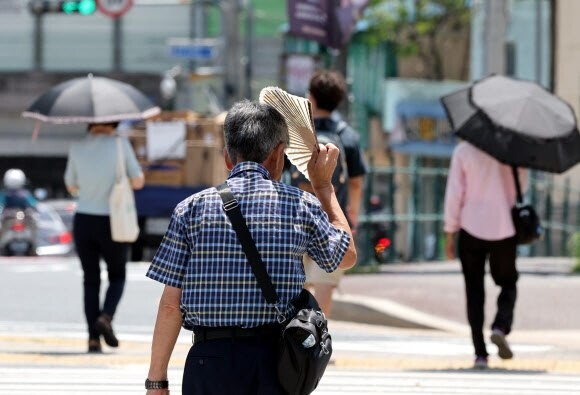 폭염경보가 내려진 7월31일 부산진구 부산시민공원 앞 횡단보도를 시민이 부채를 들고 햇볕을 가리고 있다. 연합뉴스