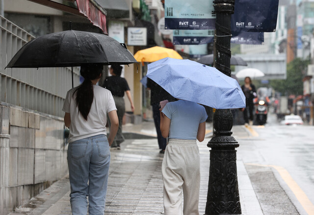 지난 13일 오후 서울 용산구 숙명여대 인근에서 시민들이 우산을 쓰고 걸어가고 있다. 연합뉴스