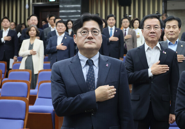 홍익표 더불어민주당 원내대표를 비롯한 의원들이 30일 국회에서 열린 의원총회에서 국기에 경례하고 있다. 연합뉴스