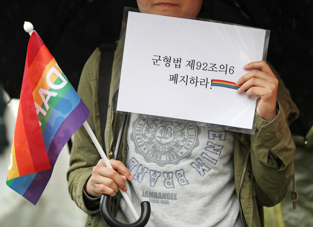 2018년 5월12일 국제성소수자 혐오반대의 날(5월17일, IDAHOTB - the International Day Against Homophobia, Transphobia and Biphobia)을 닷새 앞두고 서울 종로구 헌법재판소 앞에서 열린 군형법 92조 6항 삭제 촉구 기자회견에서 한 참가자가 깃발과 피켓을 들고 있다. 연합뉴스