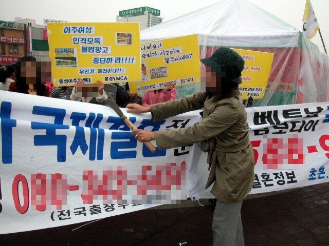 2006년 12월 동남아에서 충남 홍성으로 시집와 생활하고 있는 한 이주여성이 7일 자신들을 상품으로 전락시키고 매매혼을 부추기는 국제결혼 알선업체의 플래카드를 낫으로 찢고 있다. 연합뉴스