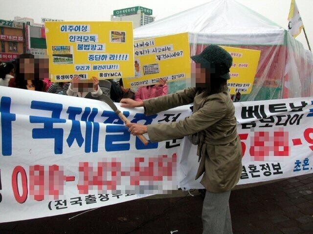 2006년 12월 동남아에서 충남 홍성으로 시집와 생활하고 있는 한 이주여성이 7일 자신들을 상품으로 전락시키고 매매혼을 부추기는 국제결혼 알선업체의 플래카드를 낫으로 찢고 있다. 연합뉴스