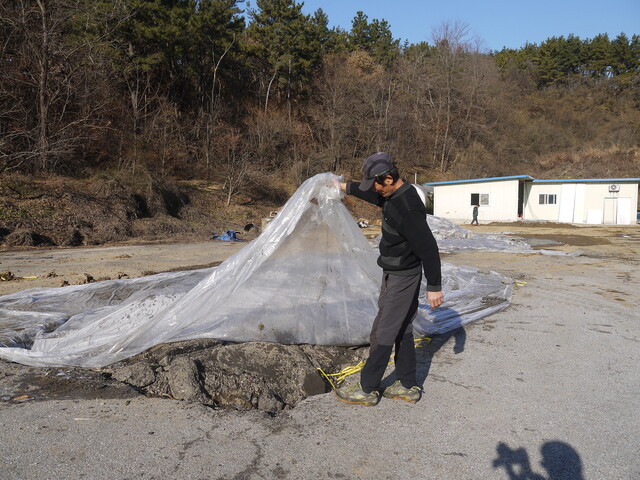 2018년 12월 익산 장점마을 한 주민이 마을 인근 비료공장 금강농산의 앞마당에 환경오염물질이 있다며 비닐을 들어 보이고 있다. 박임근 기자