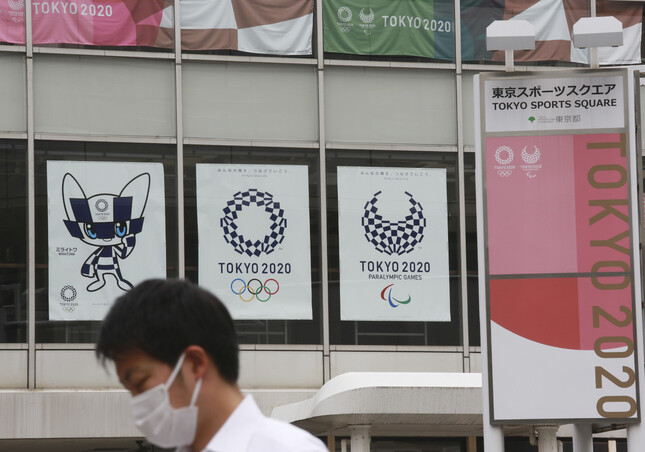 7일 일본 도쿄에서 한 남성이 올림픽 로고 앞을 지나가고 있다. 도쿄/AP 연합뉴스