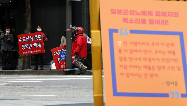 제1517차 일본군성노예제 문제해결을 위한 정기 수요시위가 열린 지난해 11월10일 낮 서울 종로구 연합뉴스 앞에서 정의기억연대에서 제작한 손팻말 너머로 정의기억연대 해체 및 수요집회 중단을 요구하는 손팻말을 든 시민들의 모습이 보인다. 김혜윤 기자 unique@hani.co.kr