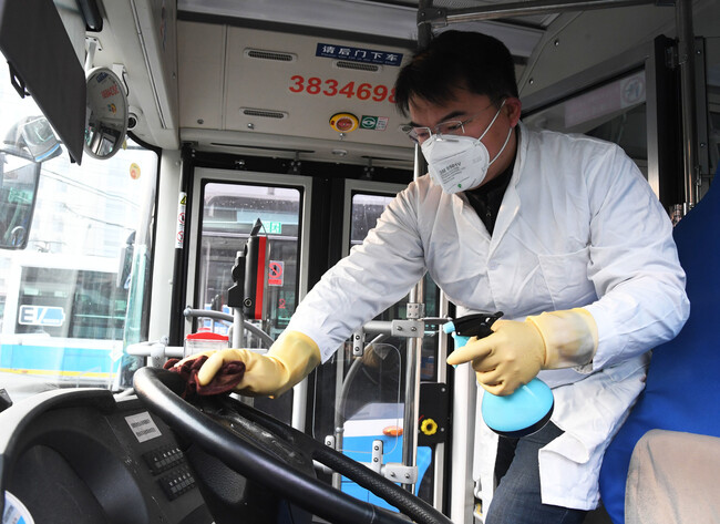 중국의 수도 베이징에서 흰색 방호복 차림에 마스크와 고글까지 갖춘 방역요원이 27일 버스 신종 코로나바이러스 감염증 확산을 막기 위해 버스 운전대를 소독약으로 닦아내고 있다. 베이징/신화 연합뉴스