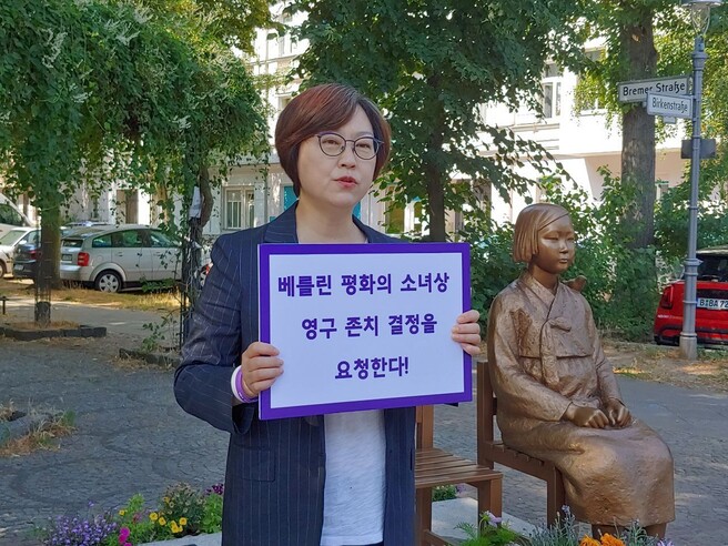 이나연 정의기억연대 이사장이 독일 베를린 미테구 평화의 소녀상 앞에서 소녀상 영구 존치 결정을 요청한다는 손팻말을 들고 있다. 정의기억연대 제공