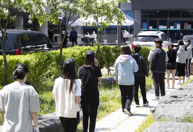 고교생 2명이 코로나19 확진 판정을 받아 등교가 하루 미뤄진 20일 오후 인천 미추홀구 옹진군청 선별진료소를 찾은 학생들을 비롯한 시민들이 순서를 기다리고 있다. 연합뉴스