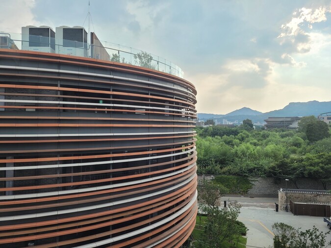 지난달 개관한 서울공예박물관 교육동 원형 건물과 그 너머 인왕산을 배경으로 보이는 송현동 땅의 푸른 숲 풍경.