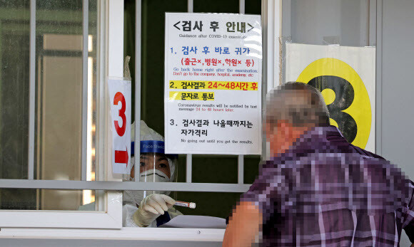 24 일 오전 서울 성북구 보건소 코로나 19 검진 클리닉에서 의료진이 시민에게 검체 채취 안내를하고있다.  연합 뉴스