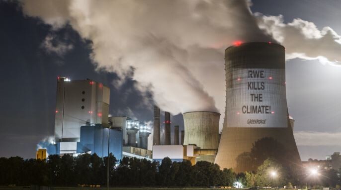 국제환경단체 그린피스가 독일 아르더블유이(RWE)의 석탄발전소 냉각탑에 ‘아르더블유이가 기후를 죽이고 있다’라는 내용의 빔 프로젝션을 투사한 모습. 그린피스 제공