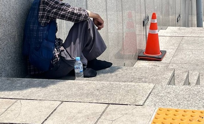 19일 오전 서울시 중구 서울역 앞 계단에 한 노숙인이 좁게 난 그늘에 앉아 있다. 곽진산 기자