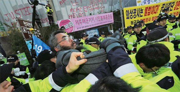 제주 강정마을회와 제주해군기지건설저지를위한전국대책위원회 등이 지난 2013년 기지 건설 사업단 앞에서 공사 중단을 요구하는 기자회견을 연 뒤 경찰에게 끌려나가고 있다. &lt;한겨레&gt; 자료사진