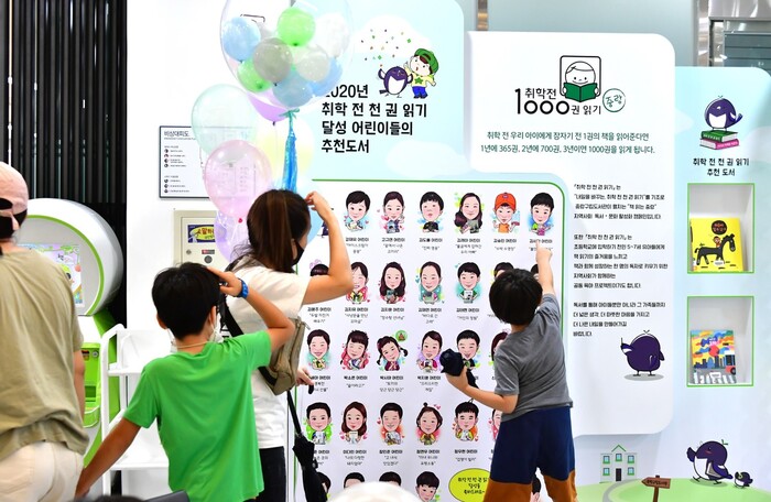 지난해 8월11일 서울 중랑구립정보도서관에서 한 어린이가 ‘취학 전 천권 읽기 달성 어린이들의 추천도서’ 포스터에 실린 자신의 캐리커처를 가리키며 기뻐하고 있다. 중랑숲어린이도서관 제공 지난해 8월11일 서울 중랑구립정보도서관에서 한 어린이가 ‘취학 전 천권 읽기 달성 어린이들의 추천도서’ 포스터에 실린 자신의 캐리커처를 가리키며 기뻐하고 있다. 중랑숲어린이도서관 제공