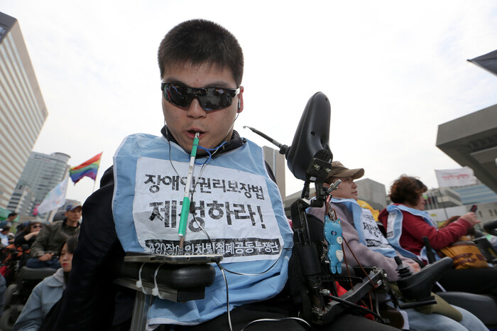 장애인의 날인 2016년 4월20일 서울 광화문광장에서 열린 ‘420 장애인차별철폐 투쟁결의대회’에 참석한 이한열씨가 입에 문 막대기를 이용해 스마트폰 문자를 입력하고 있다. 김정효 기자 hyopd@hani.co.kr 장애인의 날인 2016년 4월20일 서울 광화문광장에서 열린 ‘420 장애인차별철폐 투쟁결의대회’에 참석한 이한열씨가 입에 문 막대기를 이용해 스마트폰 문자를 입력하고 있다. 김정효 기자 hyopd@hani.co.kr